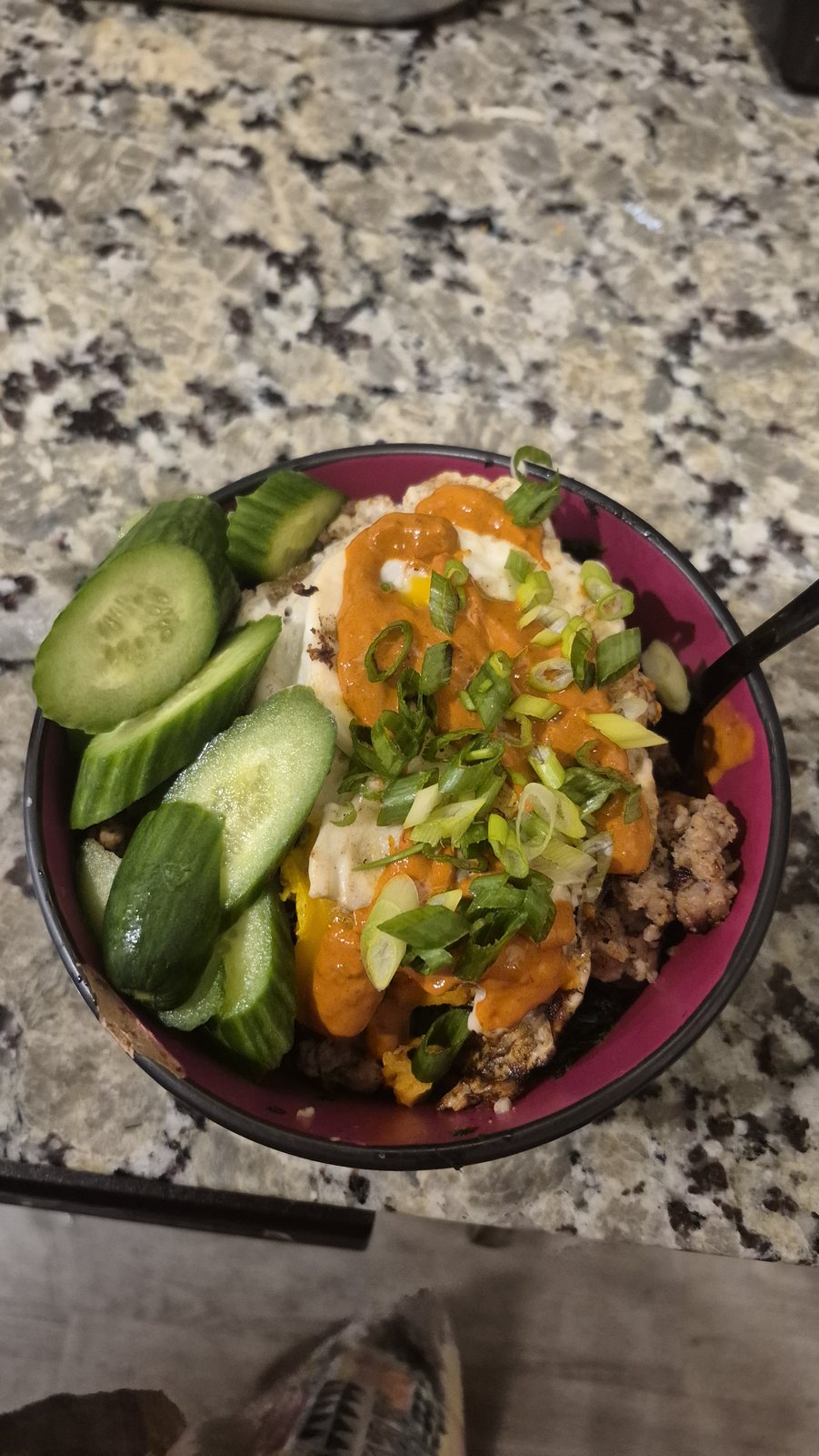 A rice bowl with cucumber, slaw and shredded cheese